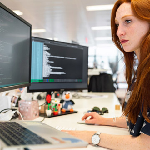 A woman working on a computer with two screens