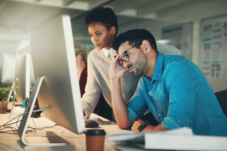 A Man And Woman Working At A Computer Station