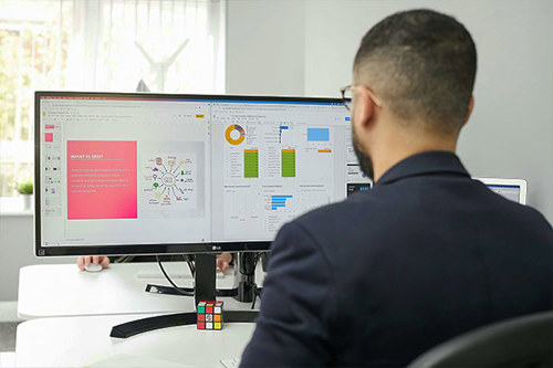 A Man Viewing Reports On A Computer Workstation