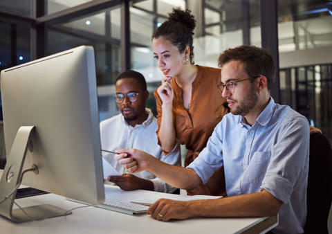 Three people at an office computer workstation