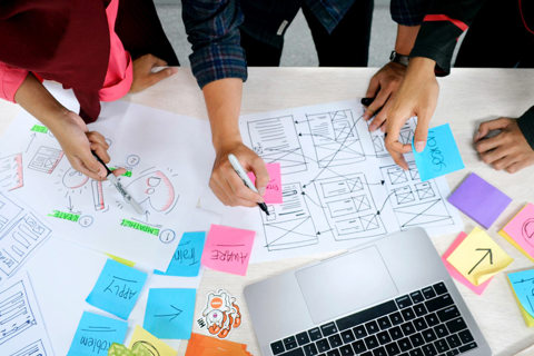 Three people working with sticky notes on a chart