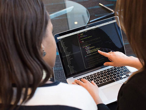 Two people looking at computer code on a laptop
