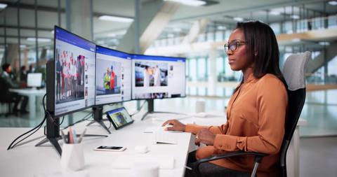 A woman at a workstation with three screens